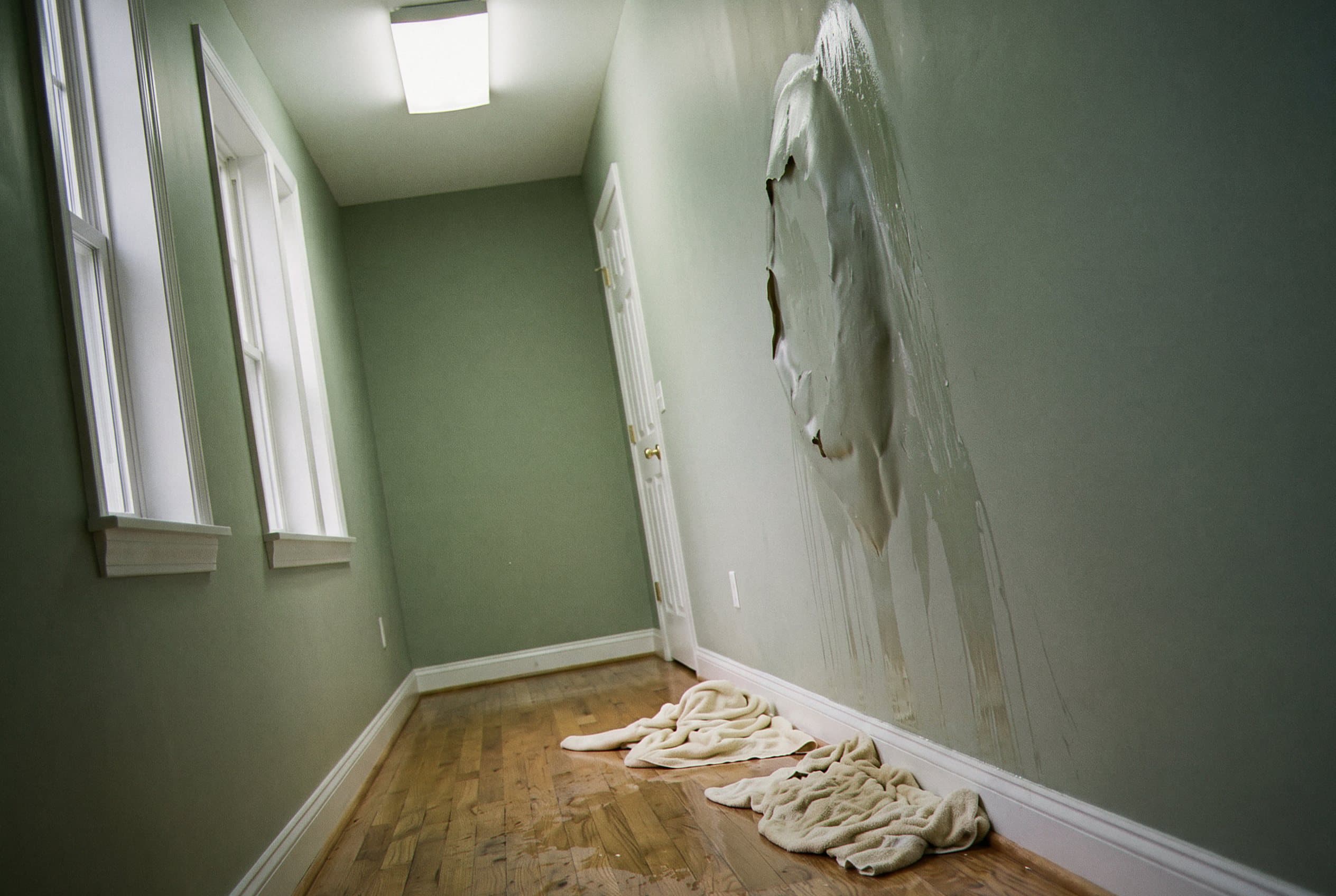 Water damage from burst pipe spreading across floor and walls
